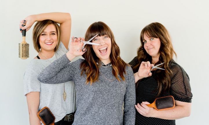 Three female salon owners holding scissors and brushes
