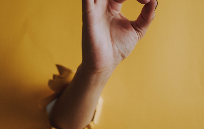 woman showing okay symbol through hole in the wall